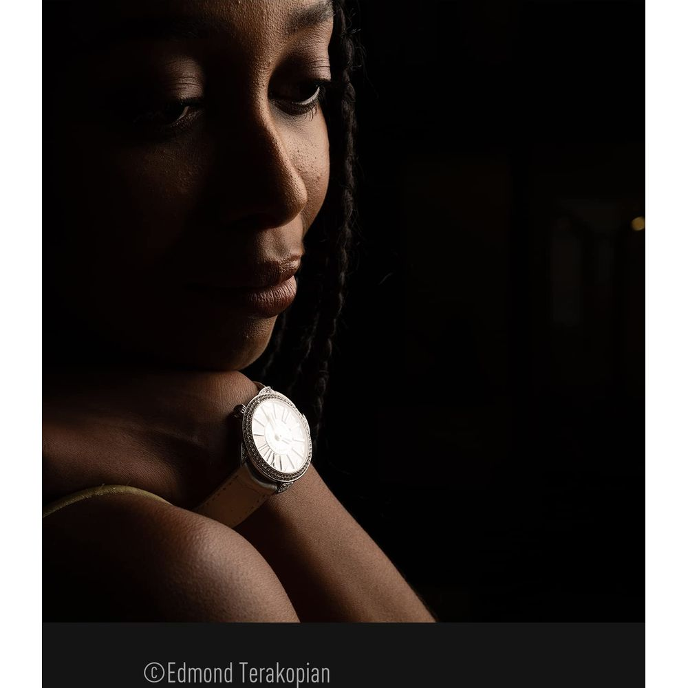 Eine Frau mit geflochtenen Haaren trägt eine silberne Uhr mit hellem Armband.