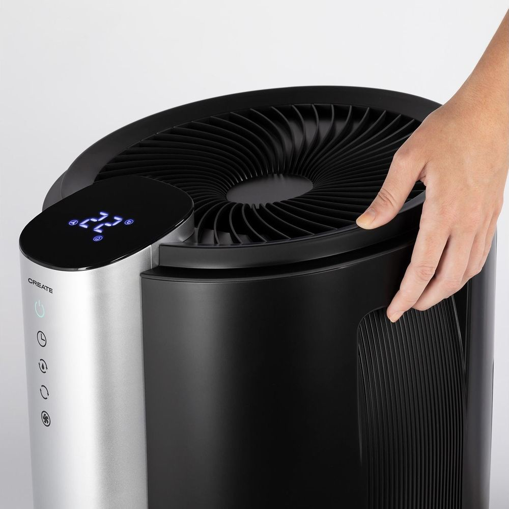 Una mano tocca il bordo superiore di un purificatore d'aria nero con corpo argentato.