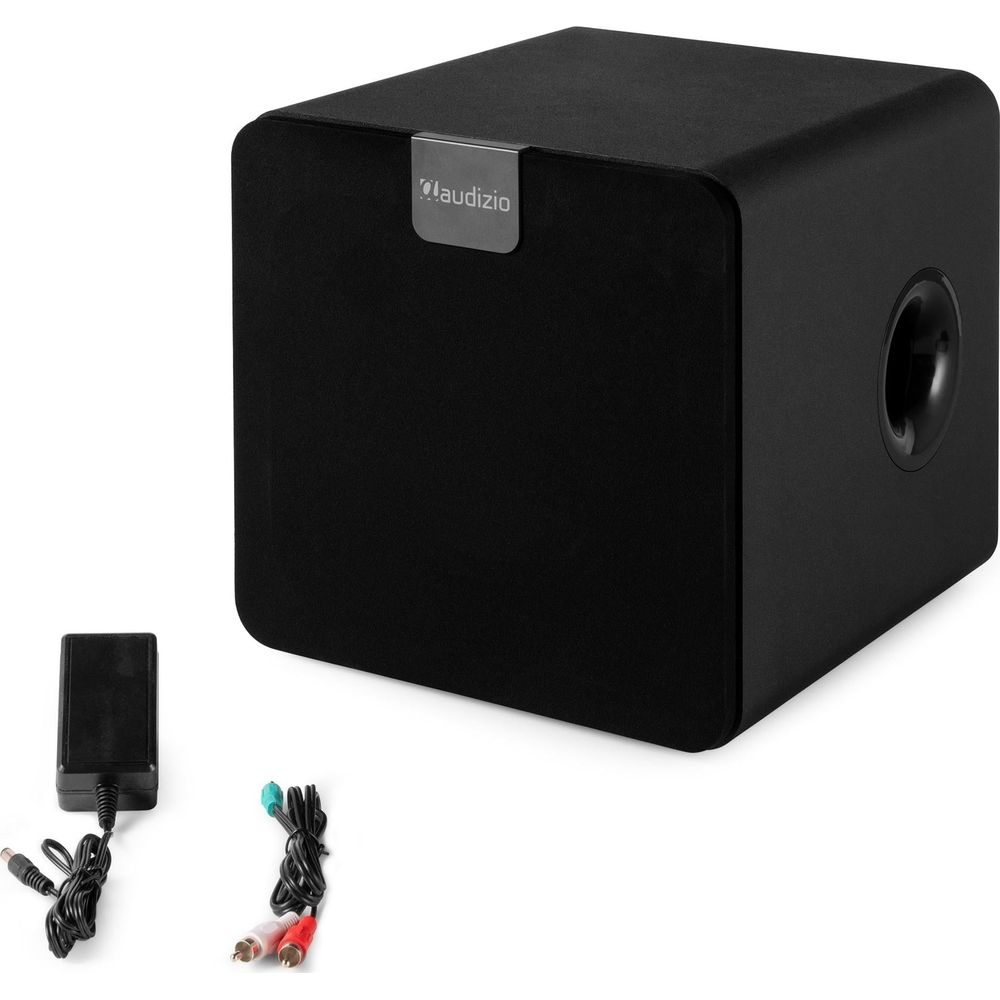 Subwoofer cuadrado negro con adaptador de corriente y cables de audio sobre fondo blanco.
