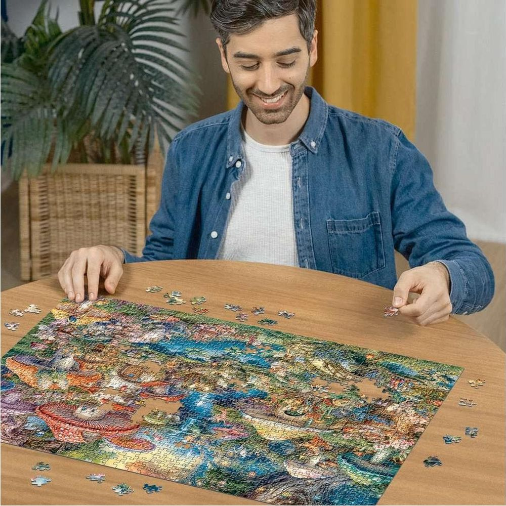Uomo in camicia blu assembla puzzle colorato su tavolo in legno. Pezzi sparsi.