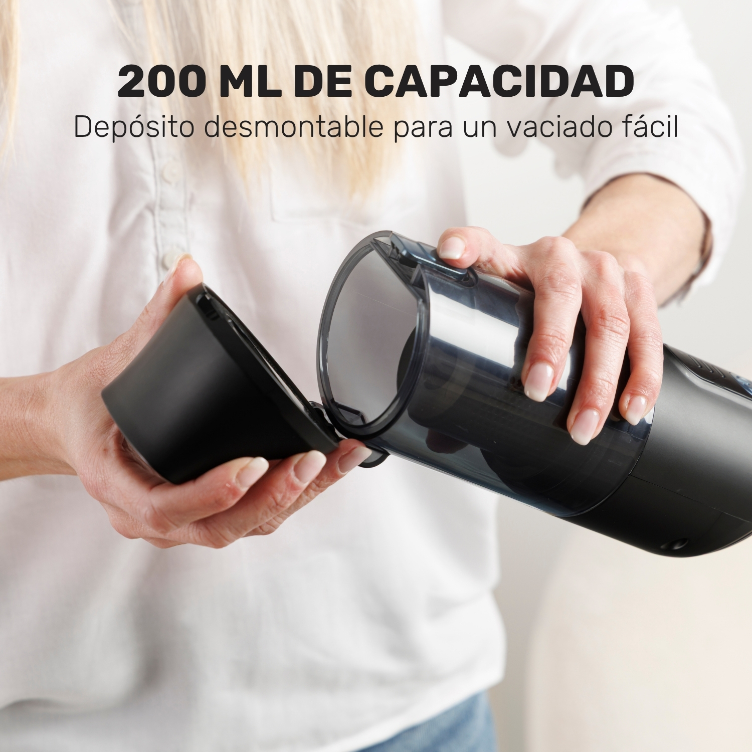Una persona sostiene un depósito de aspiradora negro desmontado.