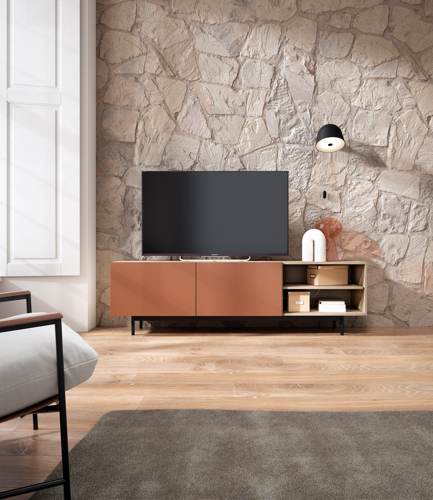 Una sala de estar con pared de piedra, consola de TV, televisor, lámpara y sillón.