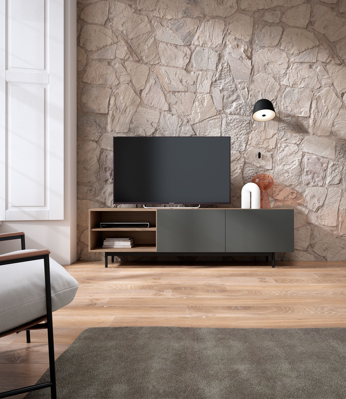 Una sala de estar con pared de piedra, televisor, aparador, sillón y alfombra.