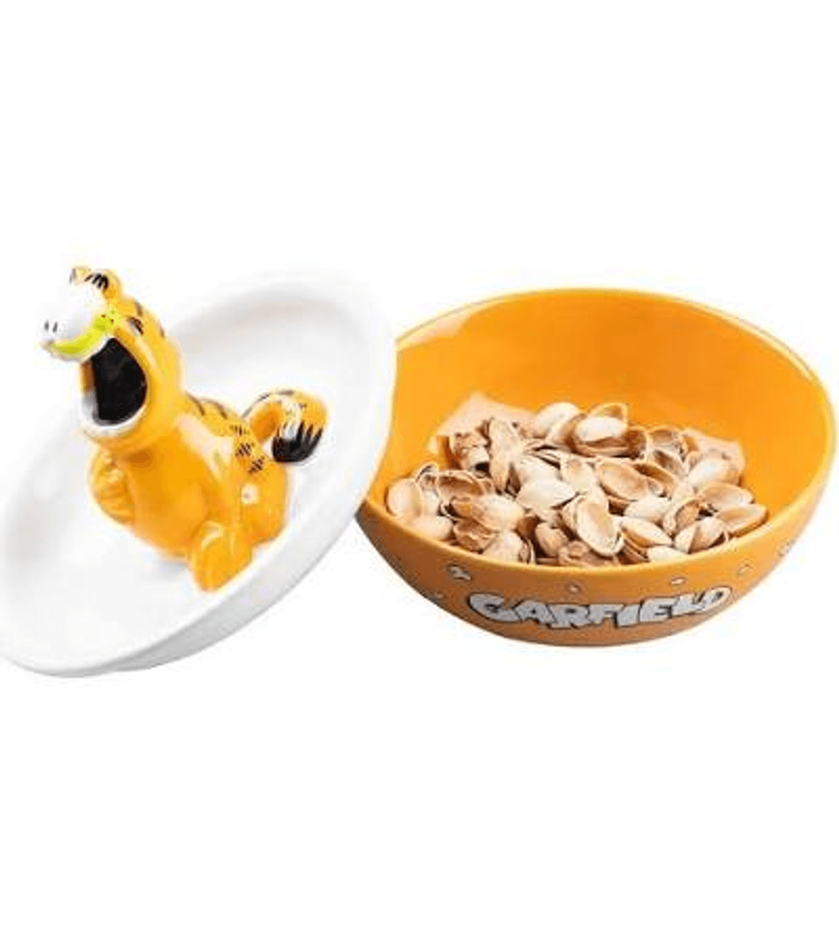 Una figura de Garfield en un plato blanco junto a un cuenco naranja con cáscaras de pistacho.