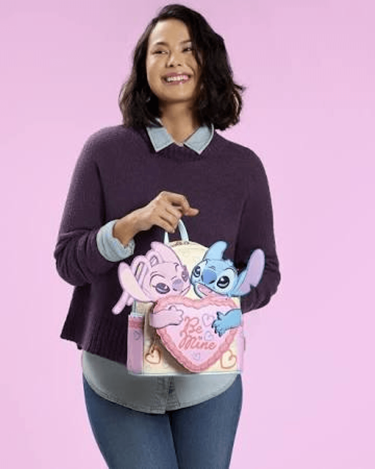 Una mujer lleva una mochila con Stitch y Angel y un corazón rosa.