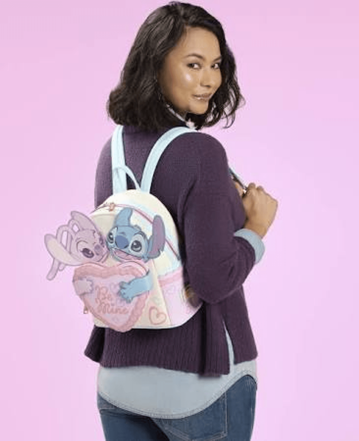 Una mochila con Stitch y Angel sobre fondo rosa.