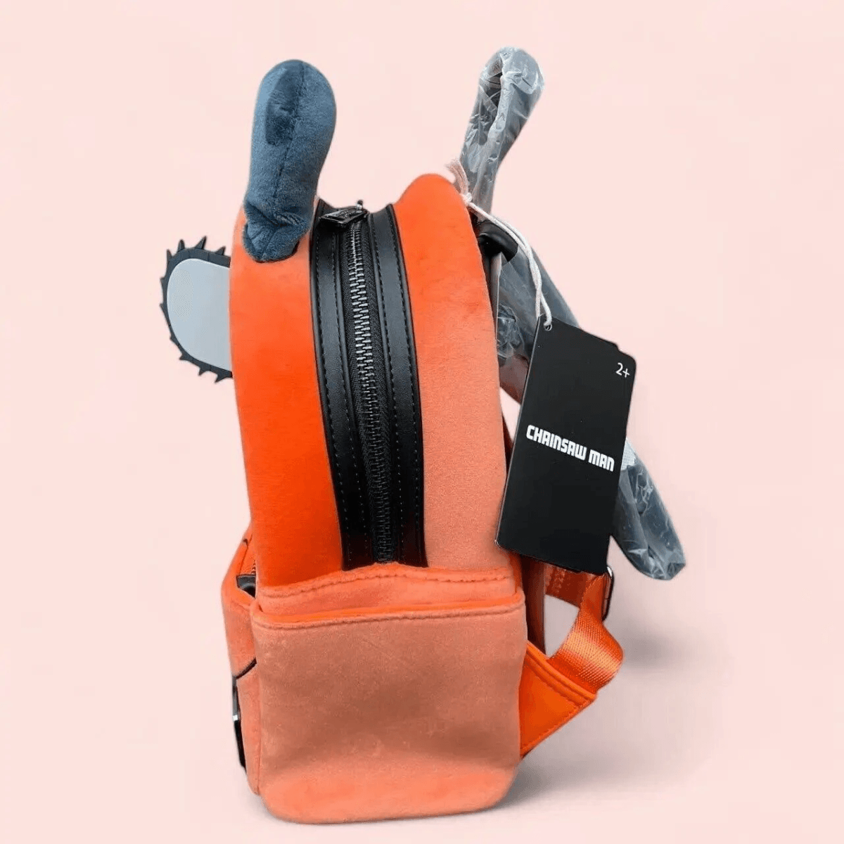 Mochila naranja de felpa con cremallera negra, detalle de motosierra y