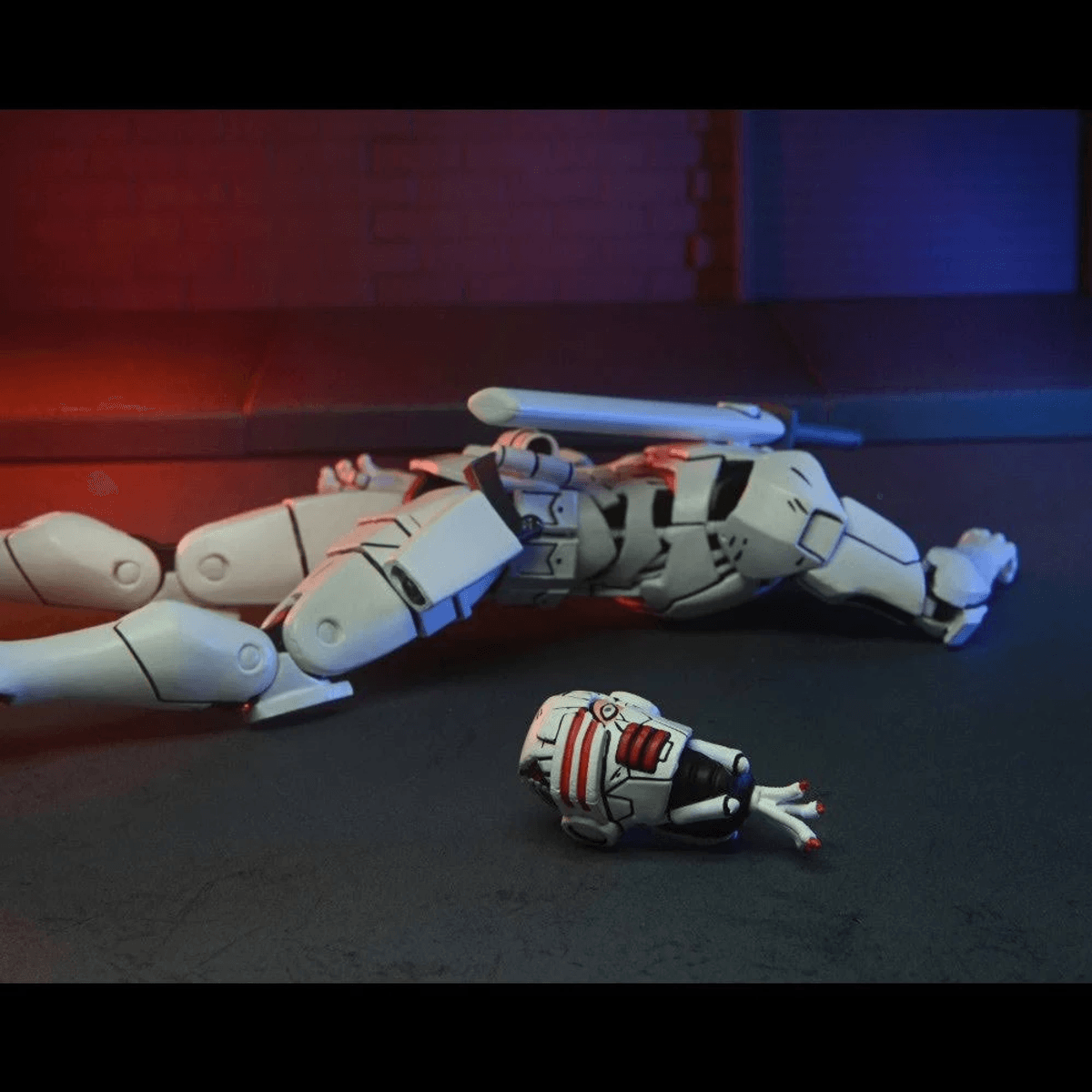 Un robot blanco yace en el suelo. Su cabeza está separada y yace cerca.