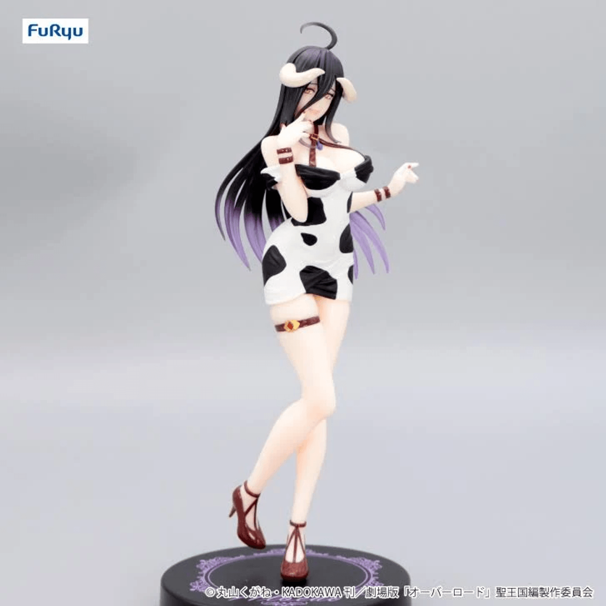 Figura de mujer con pelo negro, vestido estampado de vaca y cuernos.