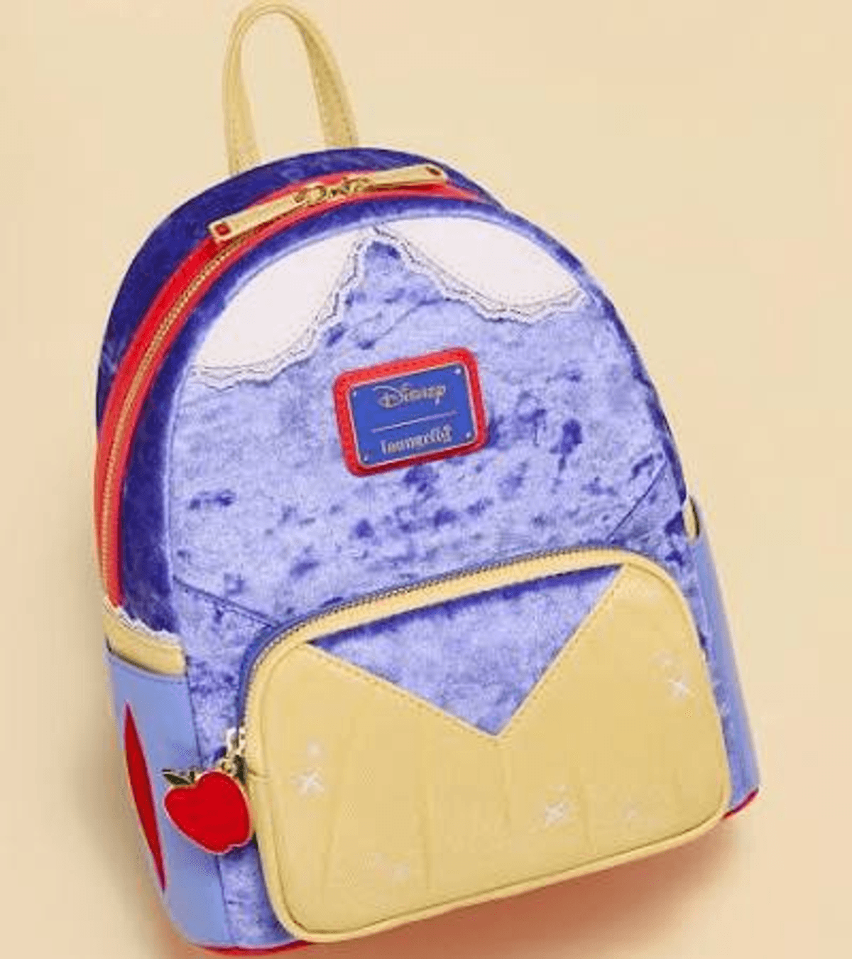 Una mochila morada con bolsillo amarillo, dije de manzana roja y logo de Disney.