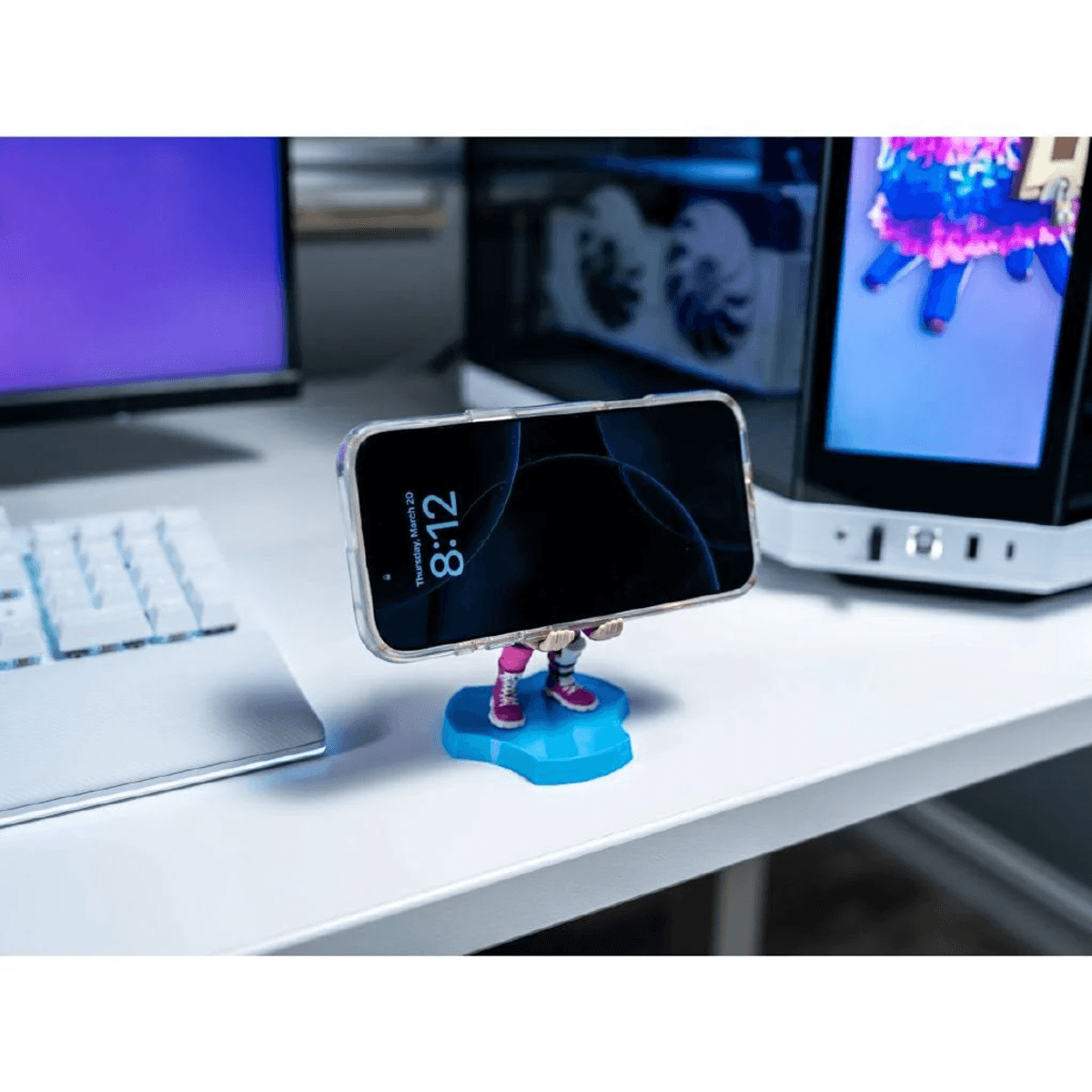 Un teléfono inteligente en un soporte de personaje azul sobre un escritorio junto a un teclado.