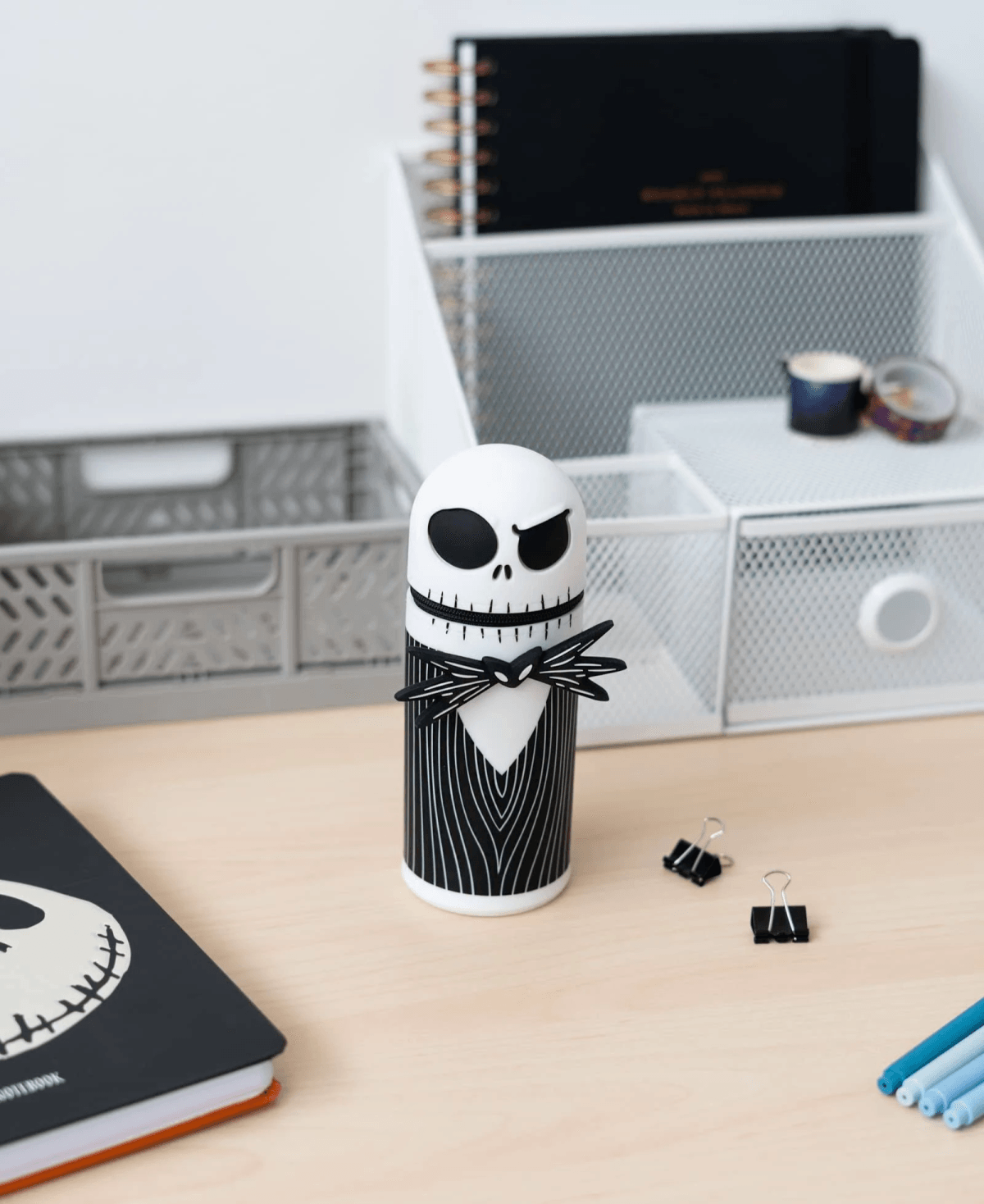 Figura de Jack Skellington sobre un escritorio con cuaderno y material de oficina.
