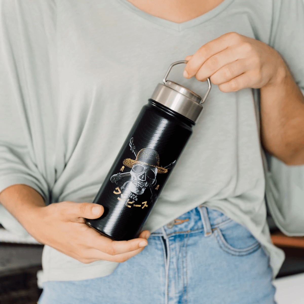 Botella de agua negra con diseño de calavera y tibias cruzadas con sombrero.