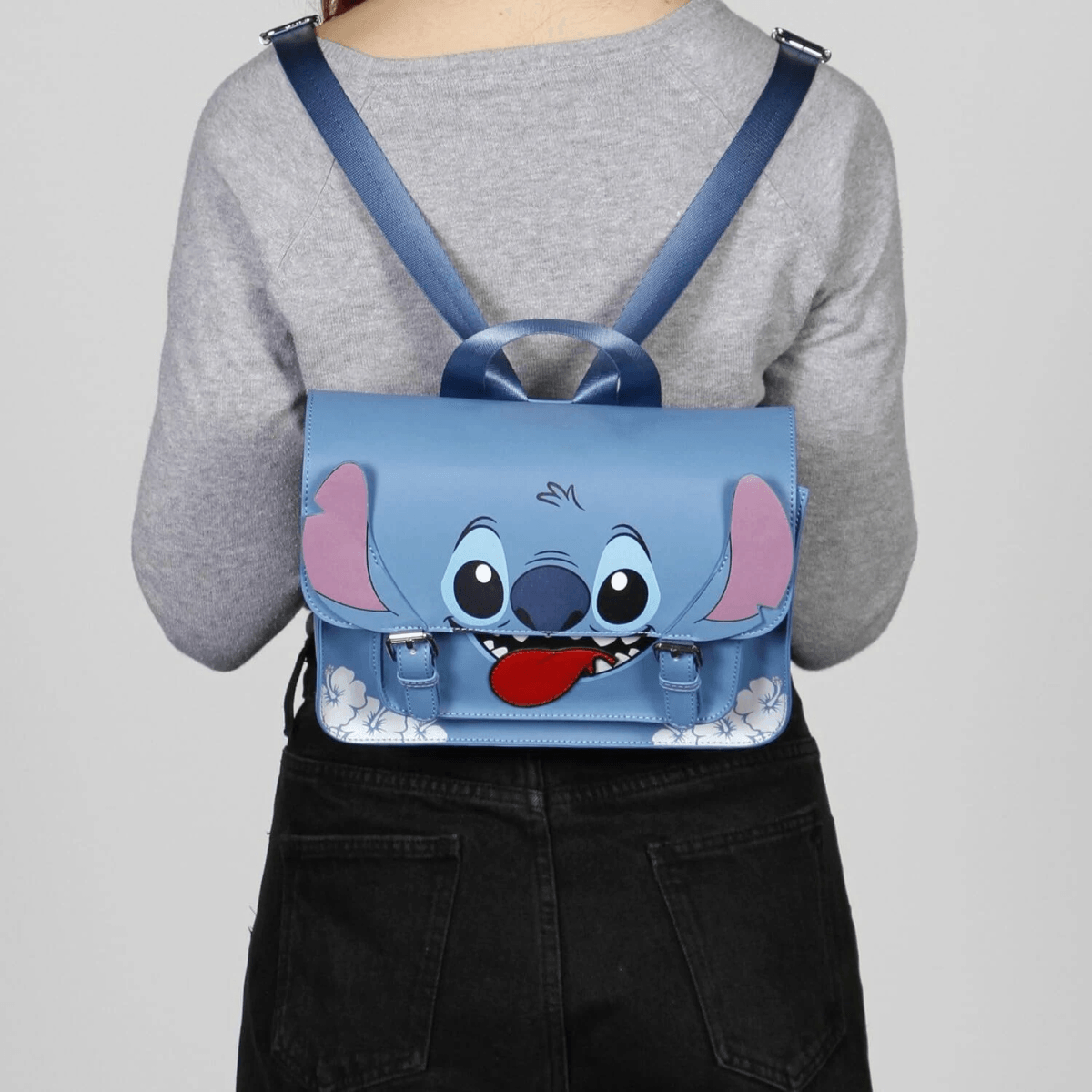 Una mochila azul de Stitch con cara graciosa y lengua colgante, llevada por una persona.