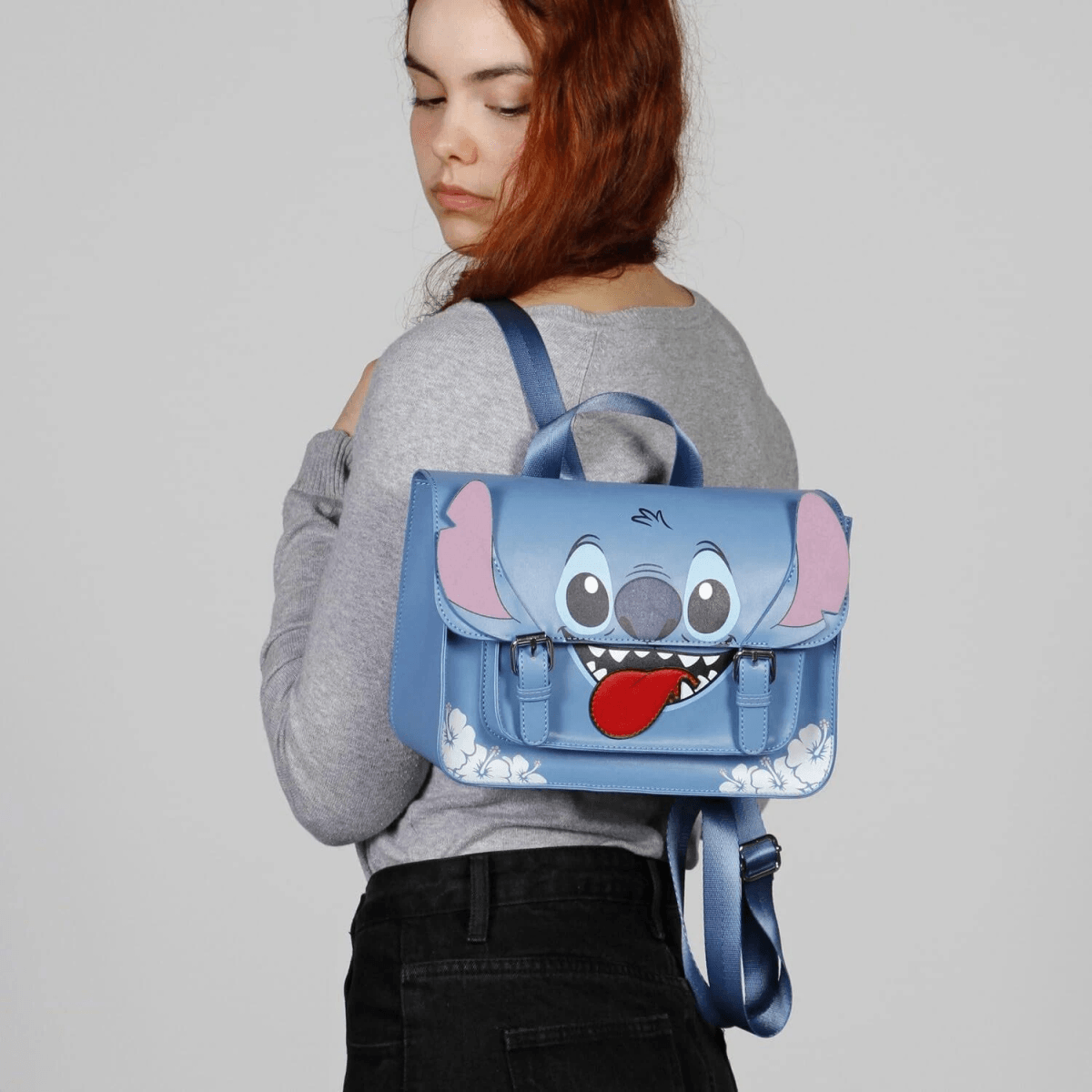 Una mochila azul con la cara de Stitch y la lengua colgando, llevada por una mujer joven.