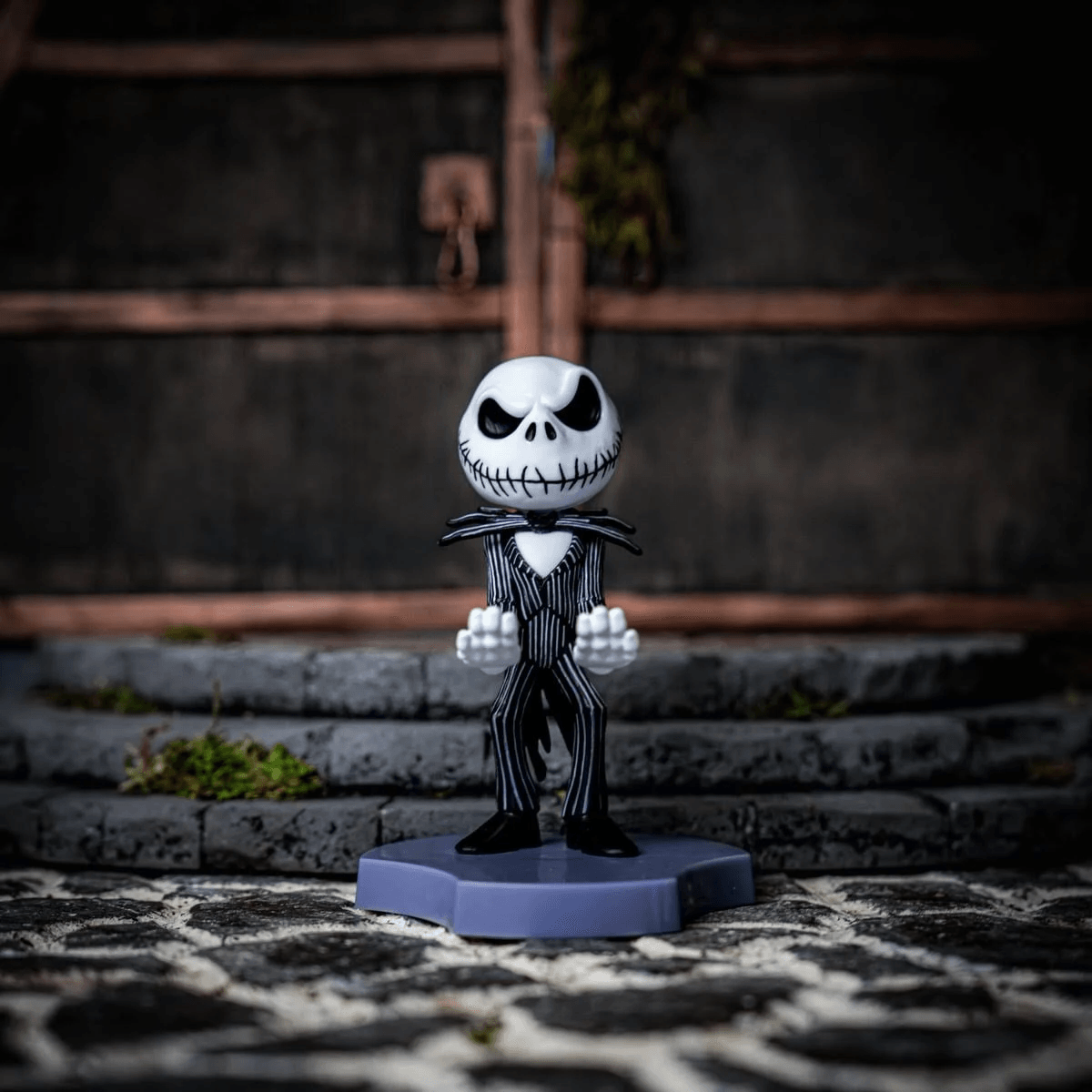 Una figura de Jack Skellington con traje de raya diplomática sobre una base lila.