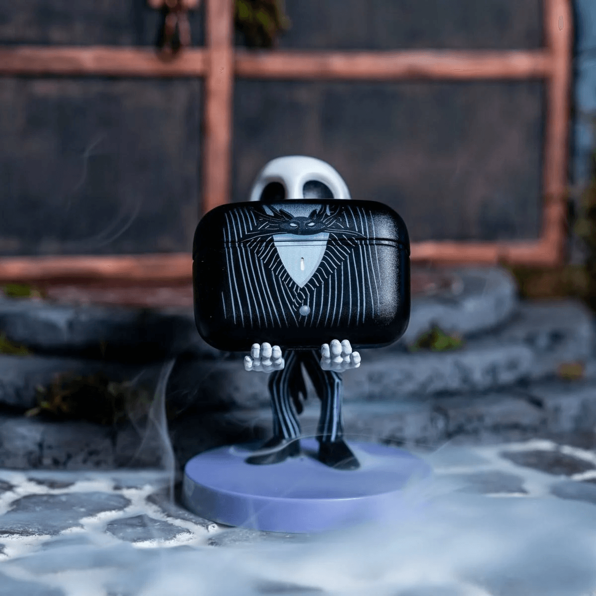 Jack Skellington Figur hält eine schwarze Hülle mit Streifenmuster in seinen Händen.