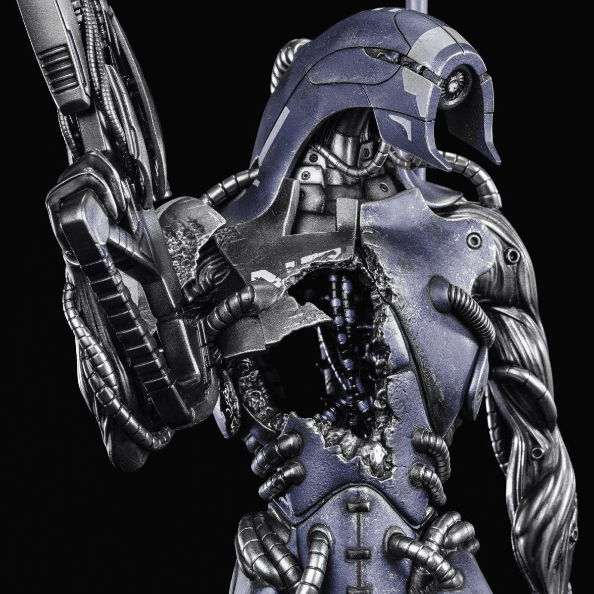 Una figura robótica azul y plateada con cableado interno expuesto y una placa pectoral desprendida.