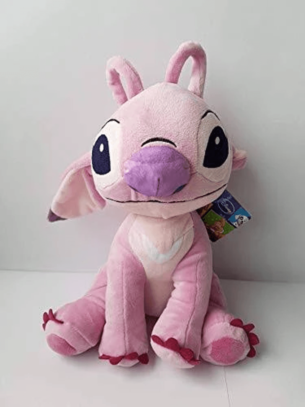 Un peluche rosa con ojos grandes y orejas largas se sienta.