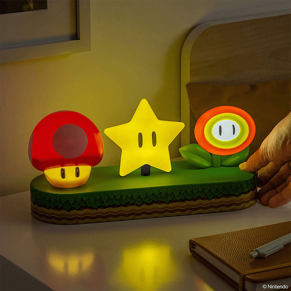 Luce notturna Super Mario: fungo, stella e fiore di fuoco su base verde.