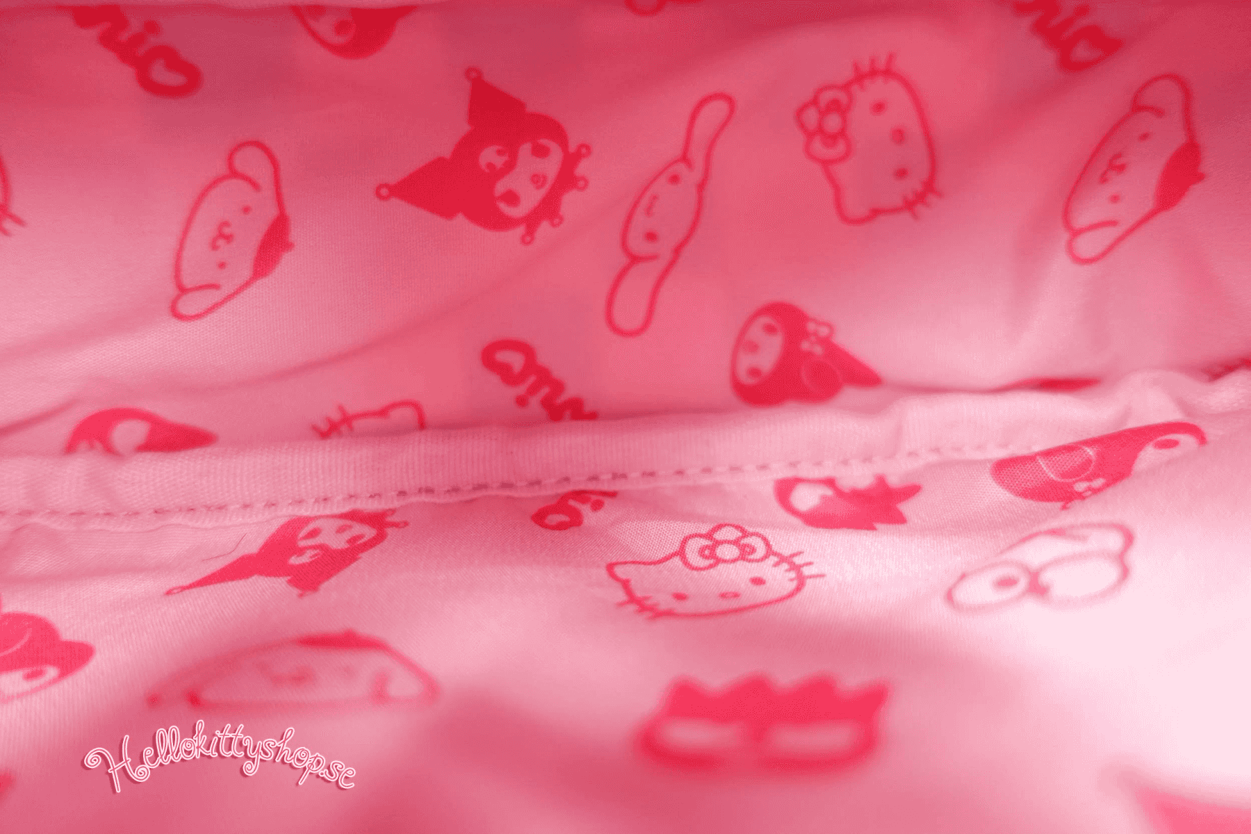 Tela rosa con estampado rojo de Hello Kitty y amigos, vista de cerca.