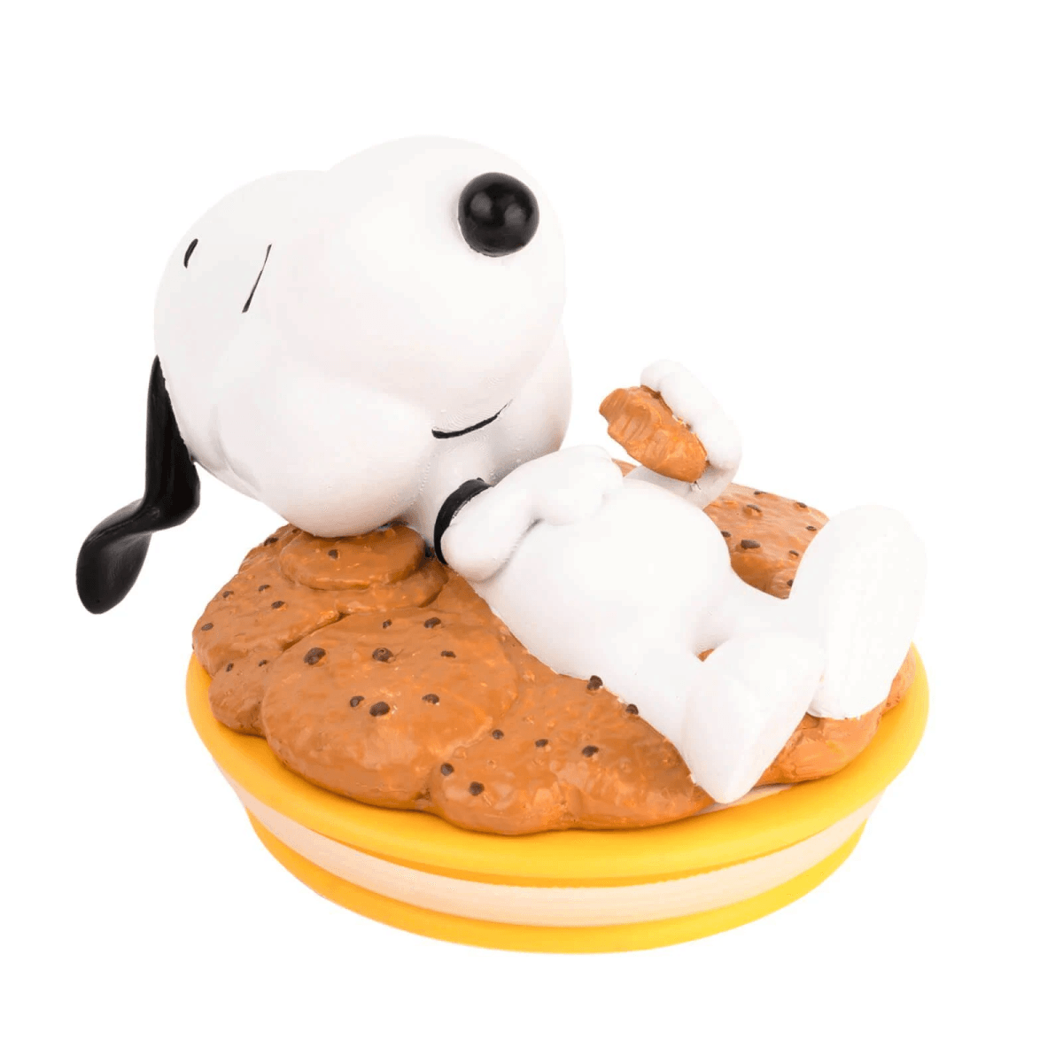 Snoopy yace sobre una galleta con chispas de chocolate, sosteniendo una galleta.