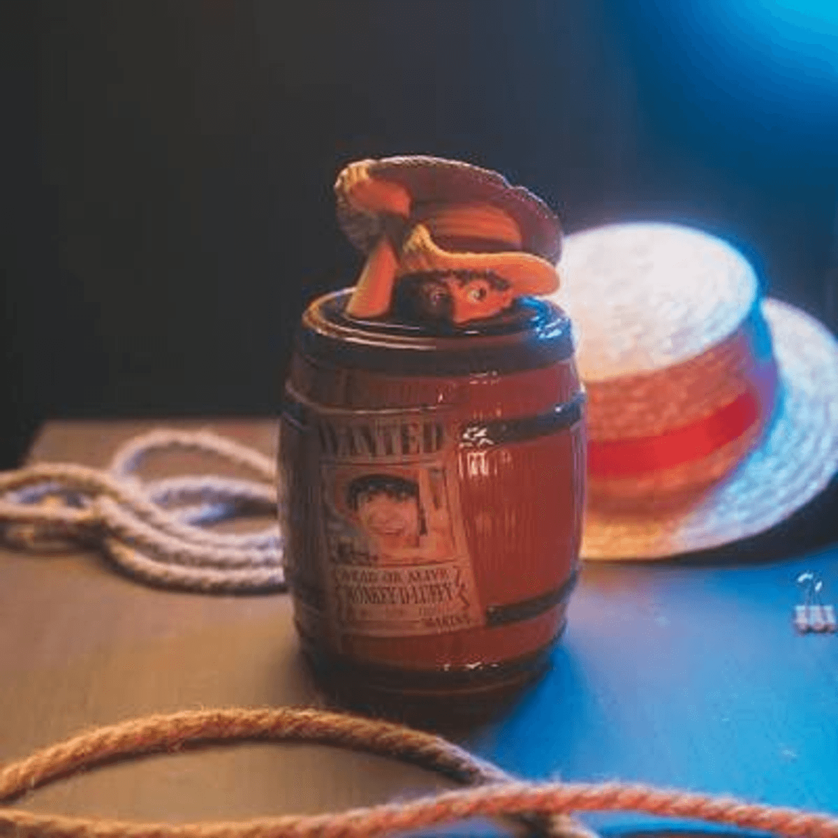Un baril "Wanted" avec une figurine et un chapeau de paille en arrière-plan.