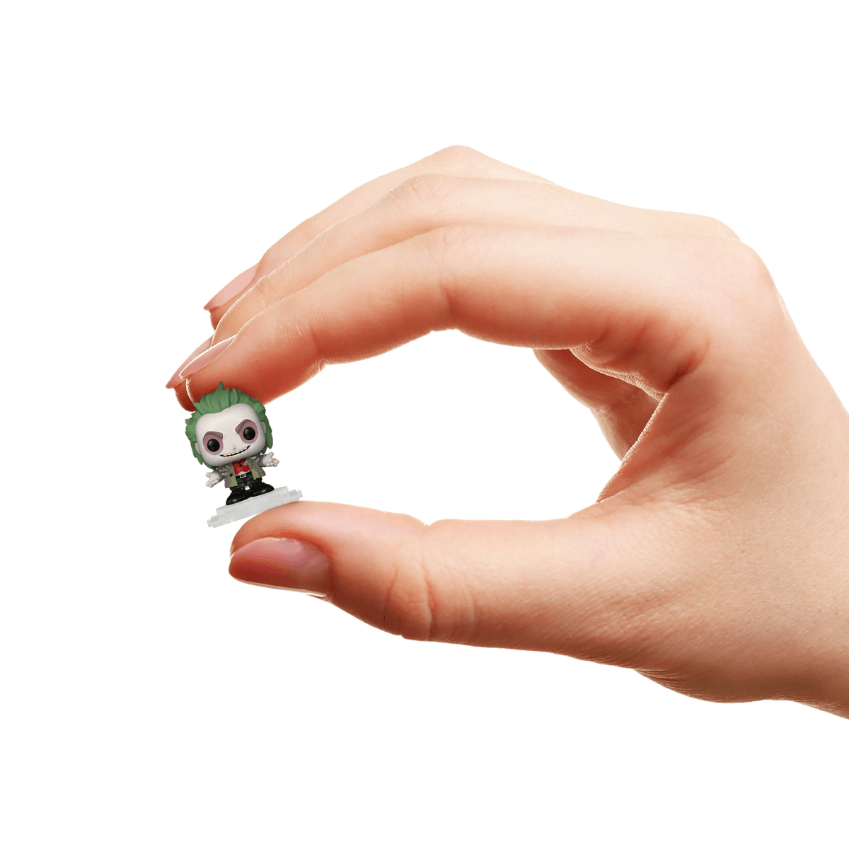 Una mano sostiene una pequeña figura del Joker con cabello verde y cara blanca.