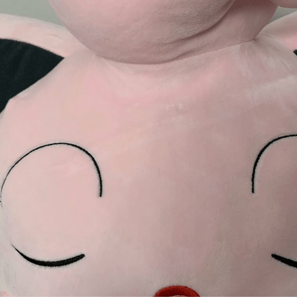 Un peluche rosa con los ojos cerrados y orejas negras.