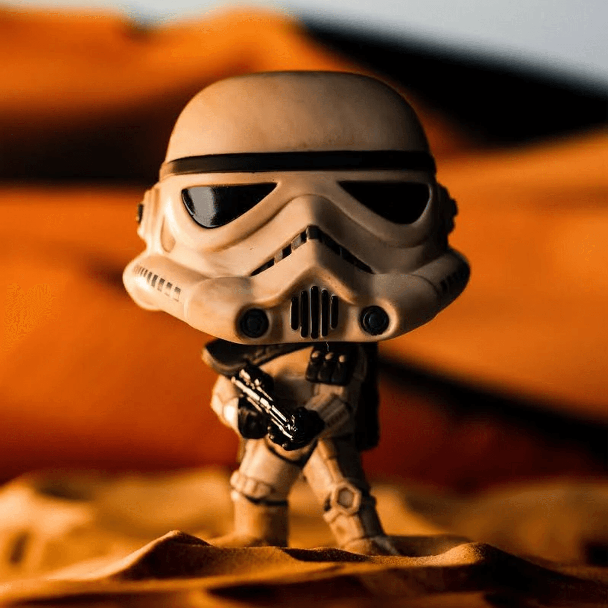 Una figura blanca de Stormtrooper de Star Wars con rifle se para en arena.