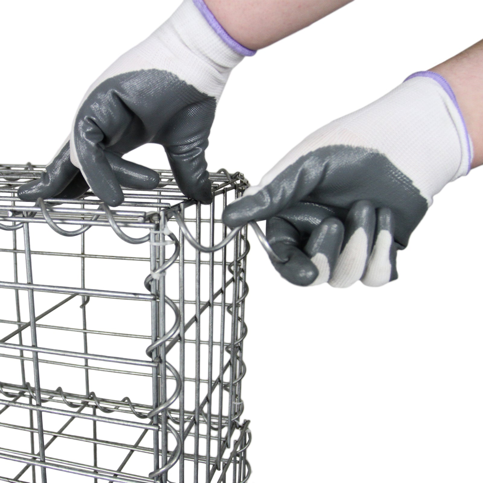 Manos con guantes arman una jaula de alambre conectando espirales.