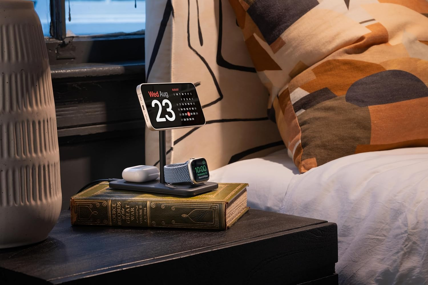 Stolik nocny ze starą książką, ładowarką, słuchawkami AirPods i Apple Watch.