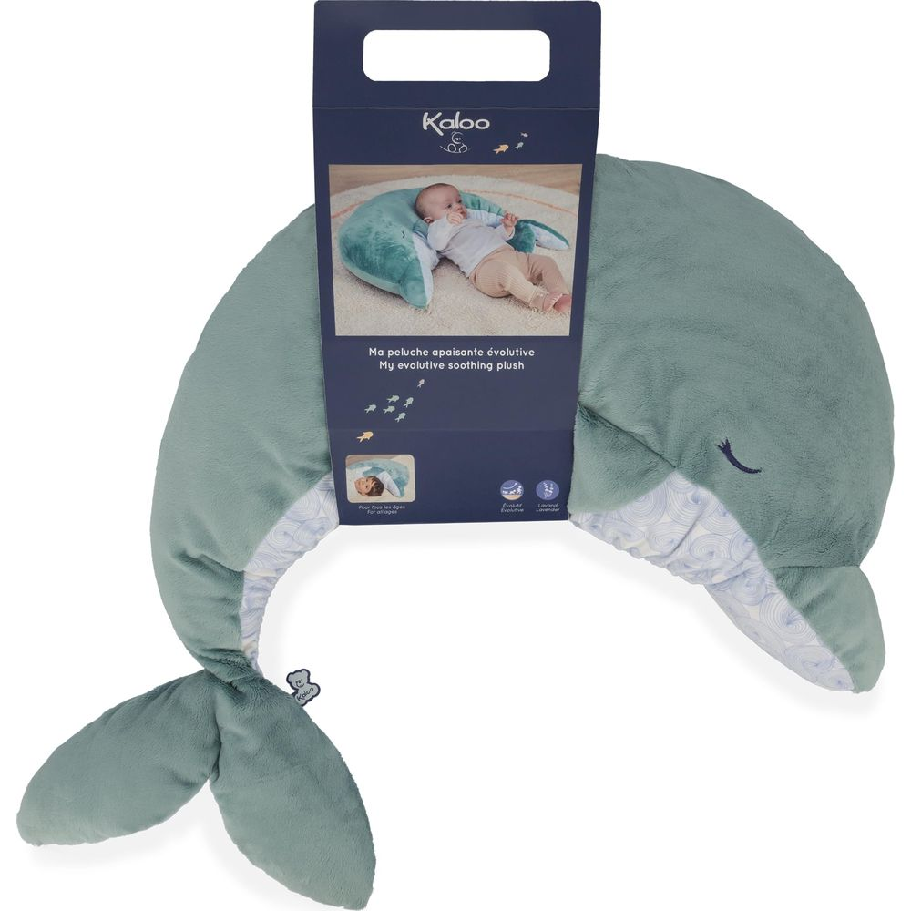 Un peluche a forma di balena verde con confezione e un bambino sopra.