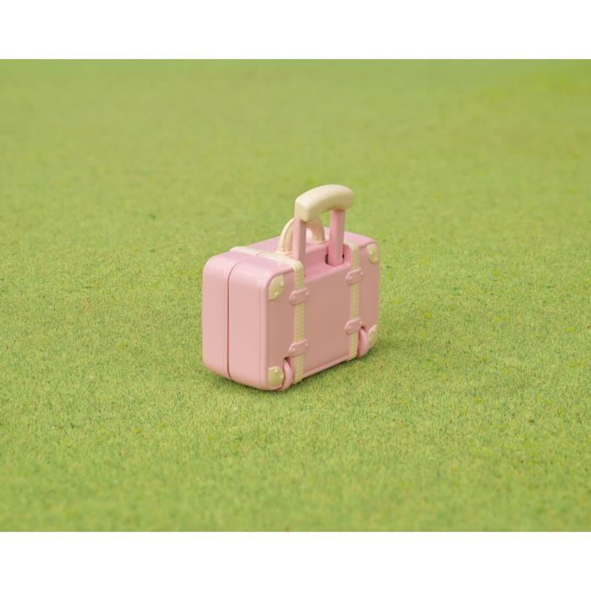 Ein kleiner rosa Koffer mit hellem Griff auf grünem Gras.