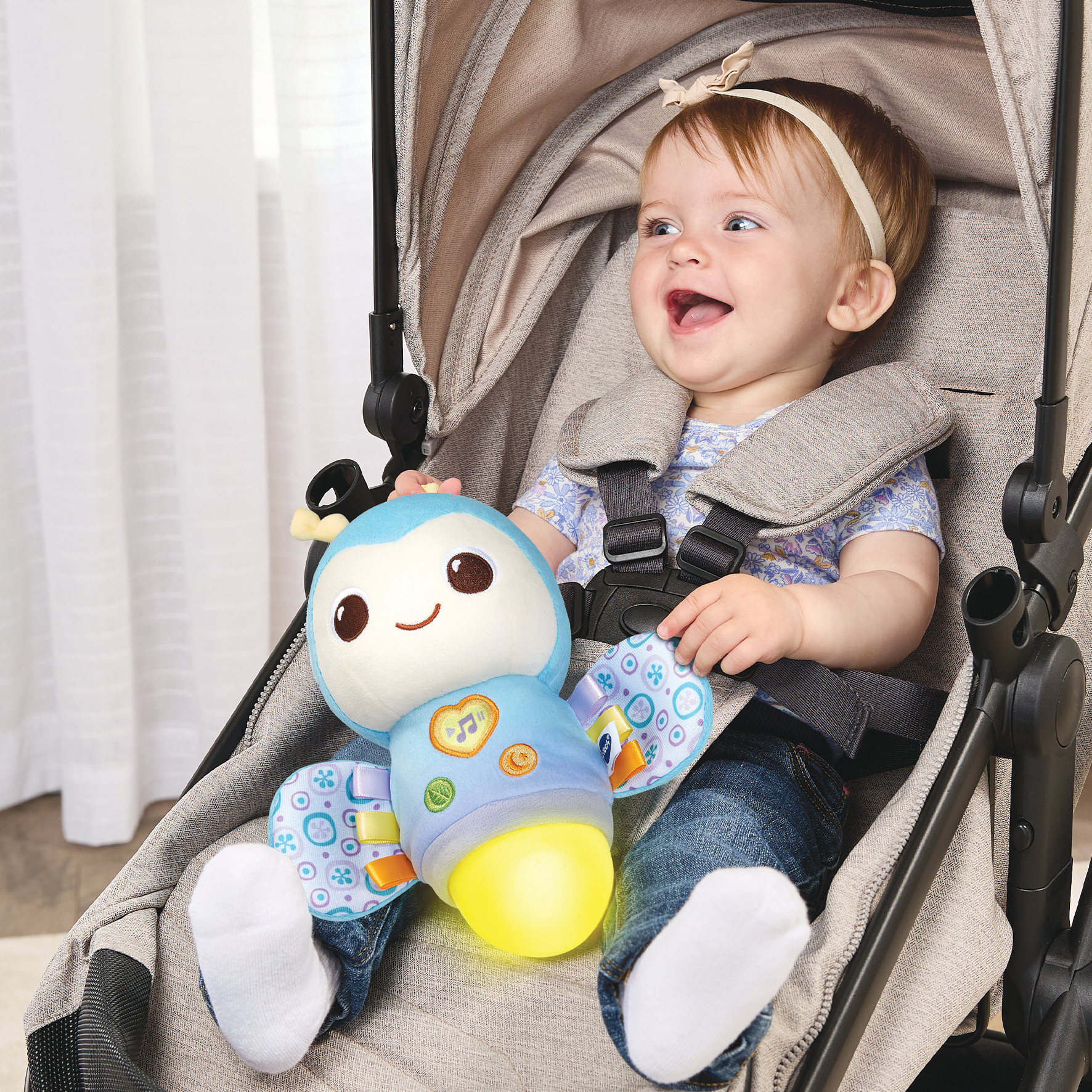 Ein Baby in einem Kinderwagen hält ein blaues, leuchtendes Spielzeug.