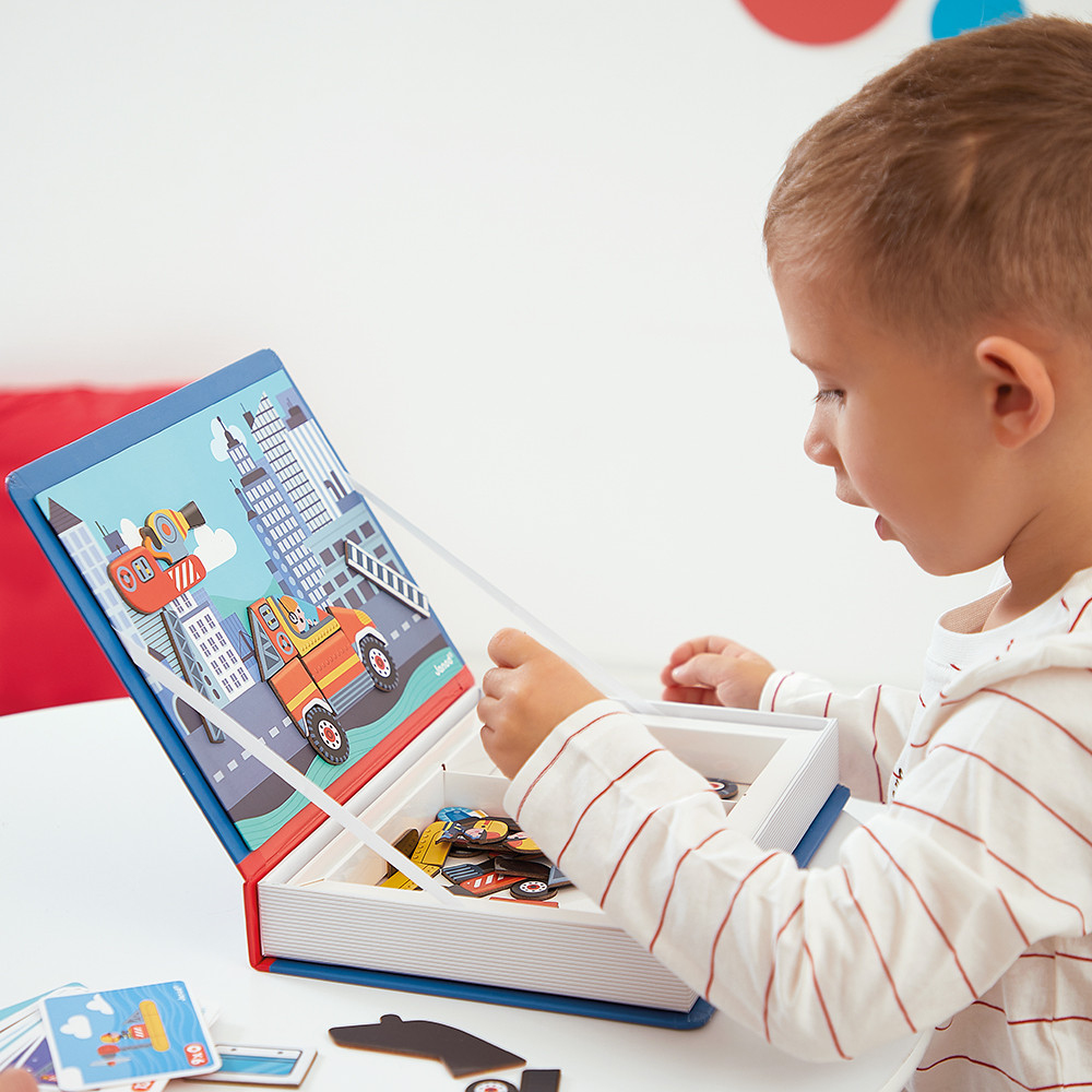 Un bambino gioca con un giocattolo magnetico con scene di città e veicoli.