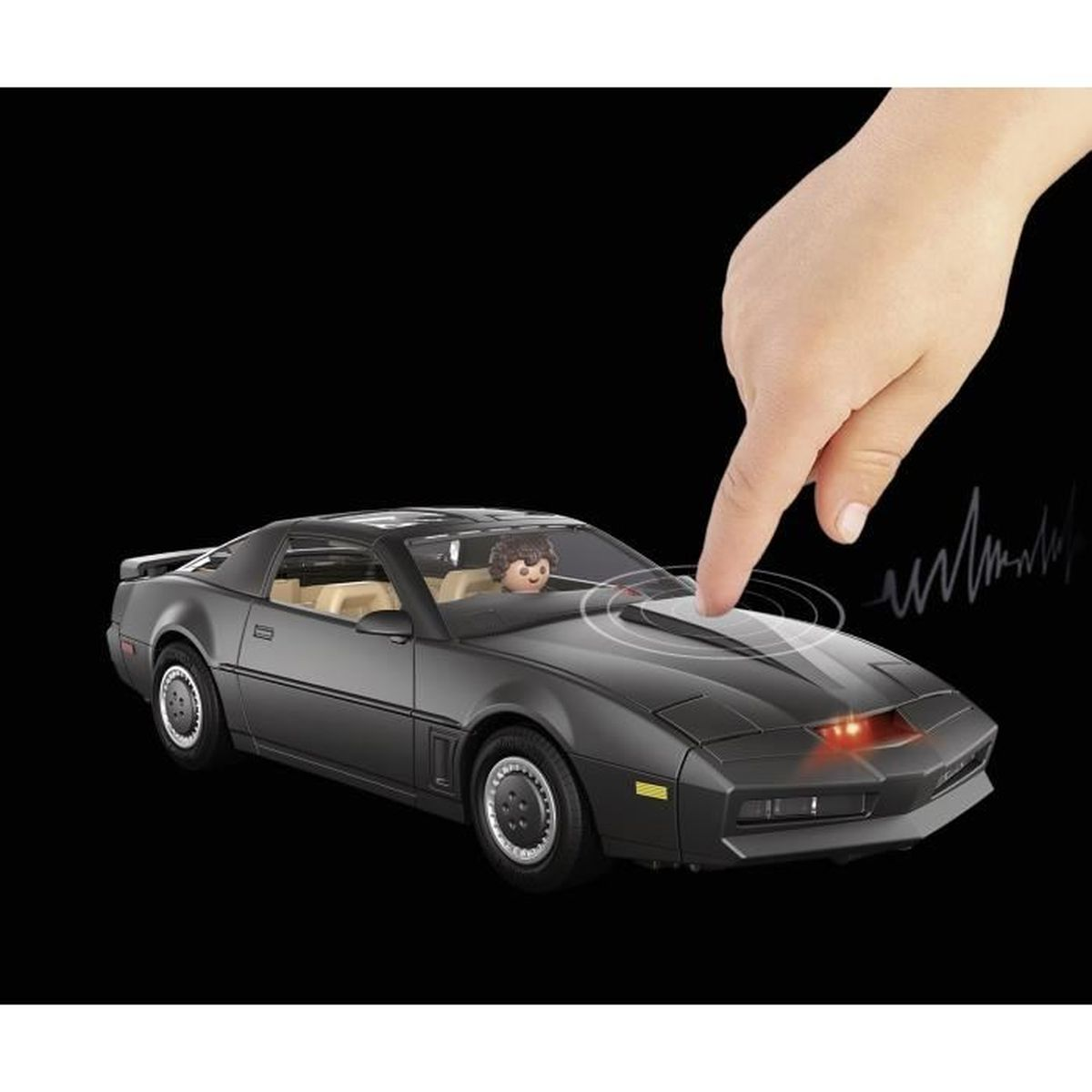 Coche de juguete negro con una figura y una mano señalándolo.