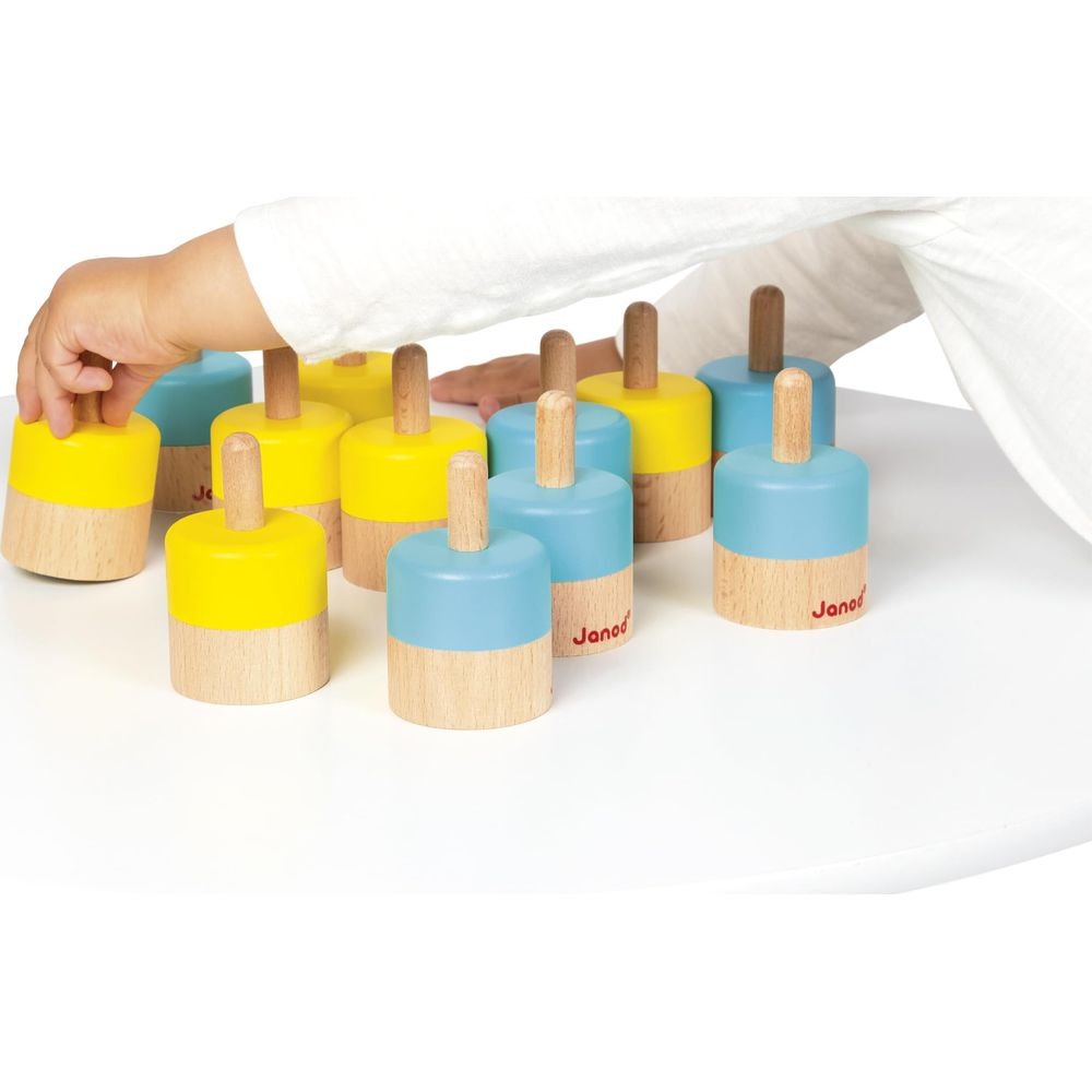 Un enfant joue avec des jouets en bois bleus et jaunes sur une table blanche.