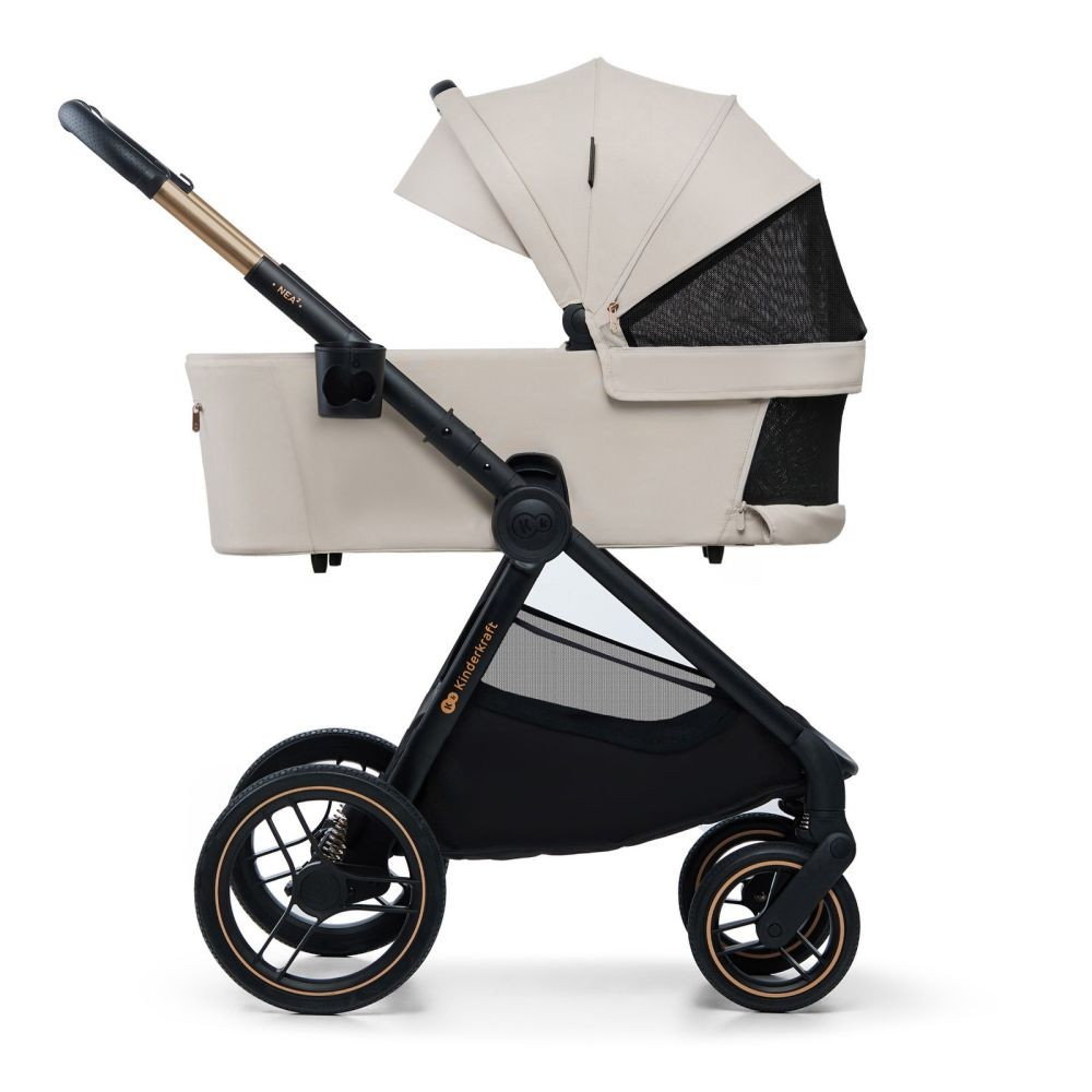 Ein cremefarbener Kinderwagen mit schwarzen Rädern und goldenen Akzenten.