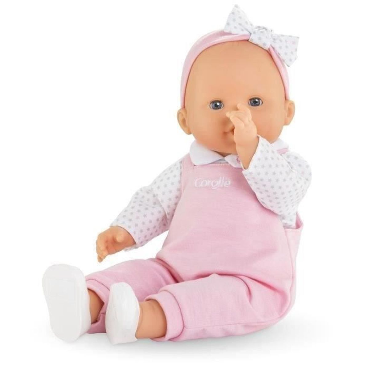 Eine Babypuppe mit rosa Latzhose und weißem Sternenoberteil sitzt.