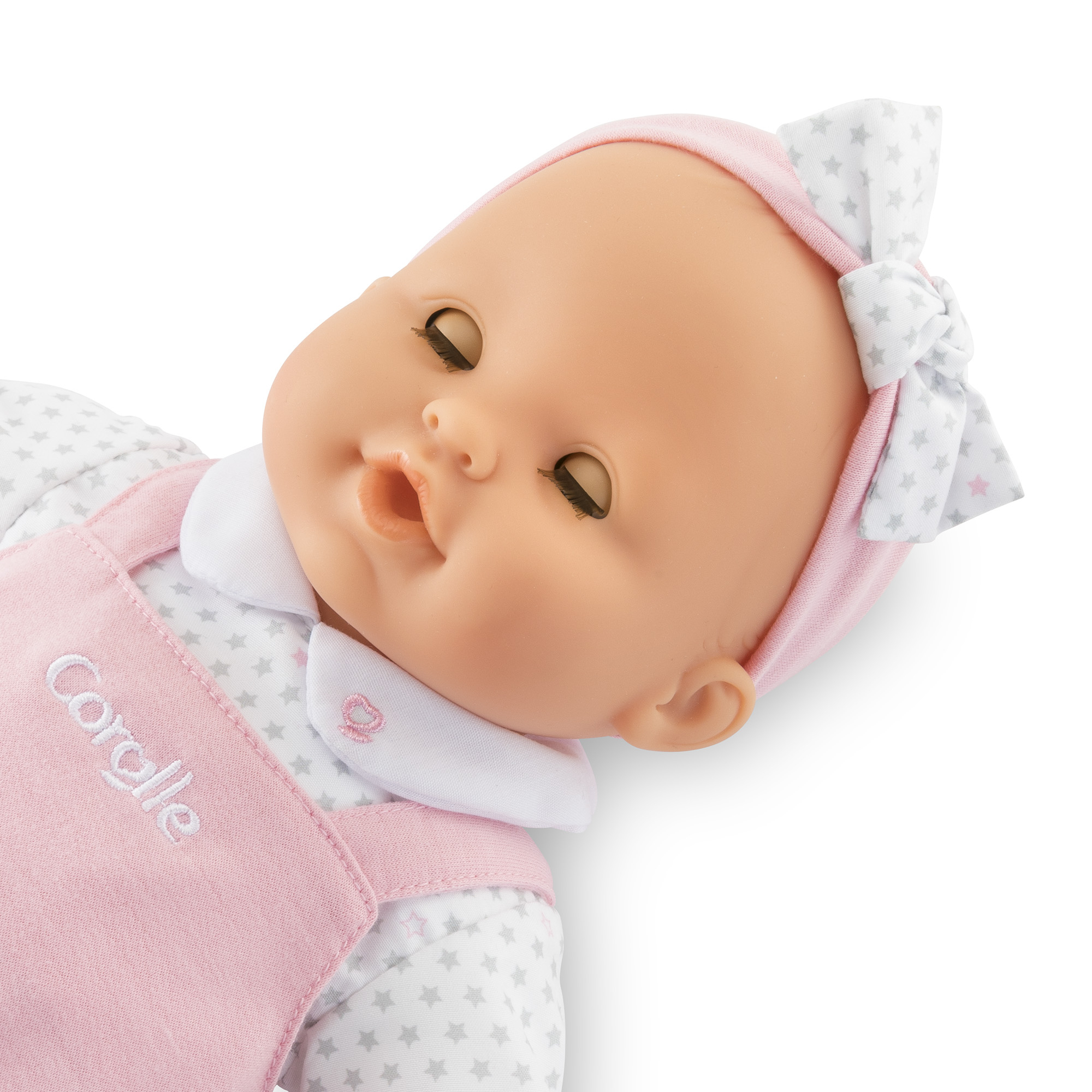 Ein Baby-Puppe mit geschlossenen Augen und einem rosa Stirnband mit Schleife.