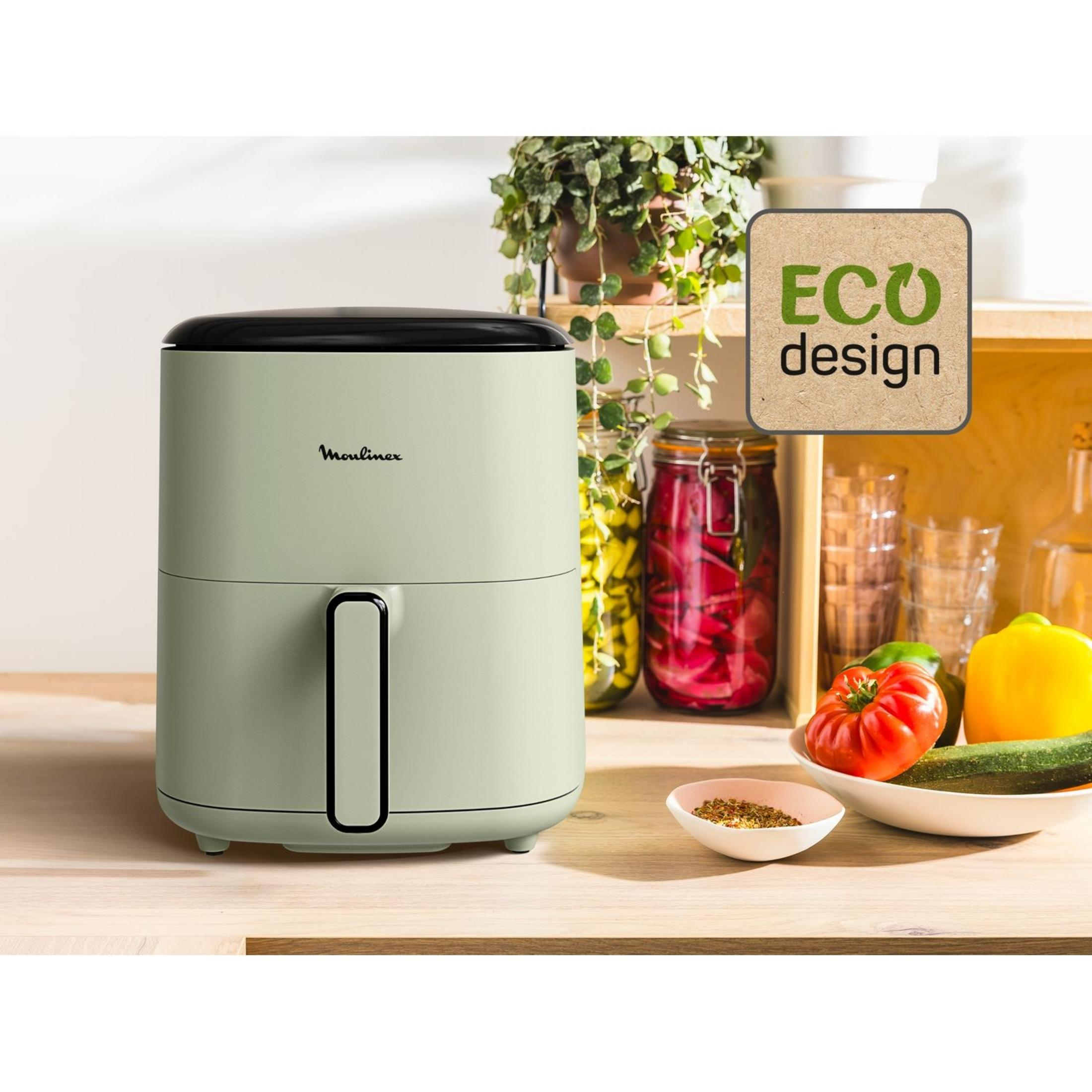 Una friggitrice ad aria verde chiaro con coperchio nero è su un bancone di legno. Verdure nelle vicinanze.