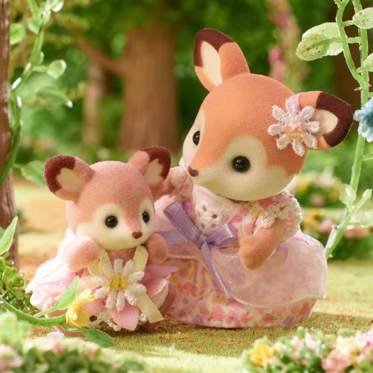 Dos figuras de zorro con vestidos rosas, una con flor en la oreja, al aire libre.