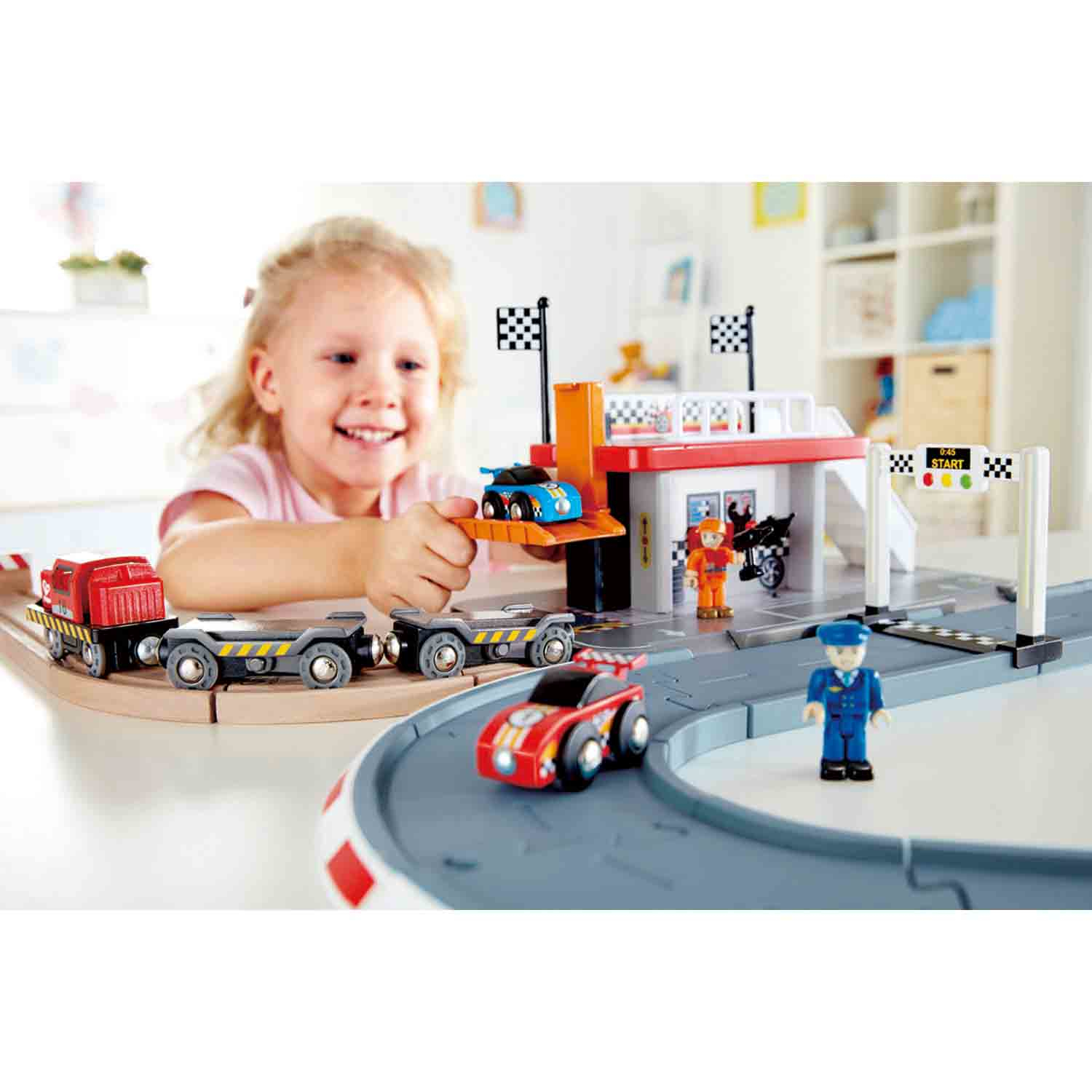 Ein Mädchen spielt mit einem Spielzeug-Autorennen und Zügen in einem Kinderzimmer.