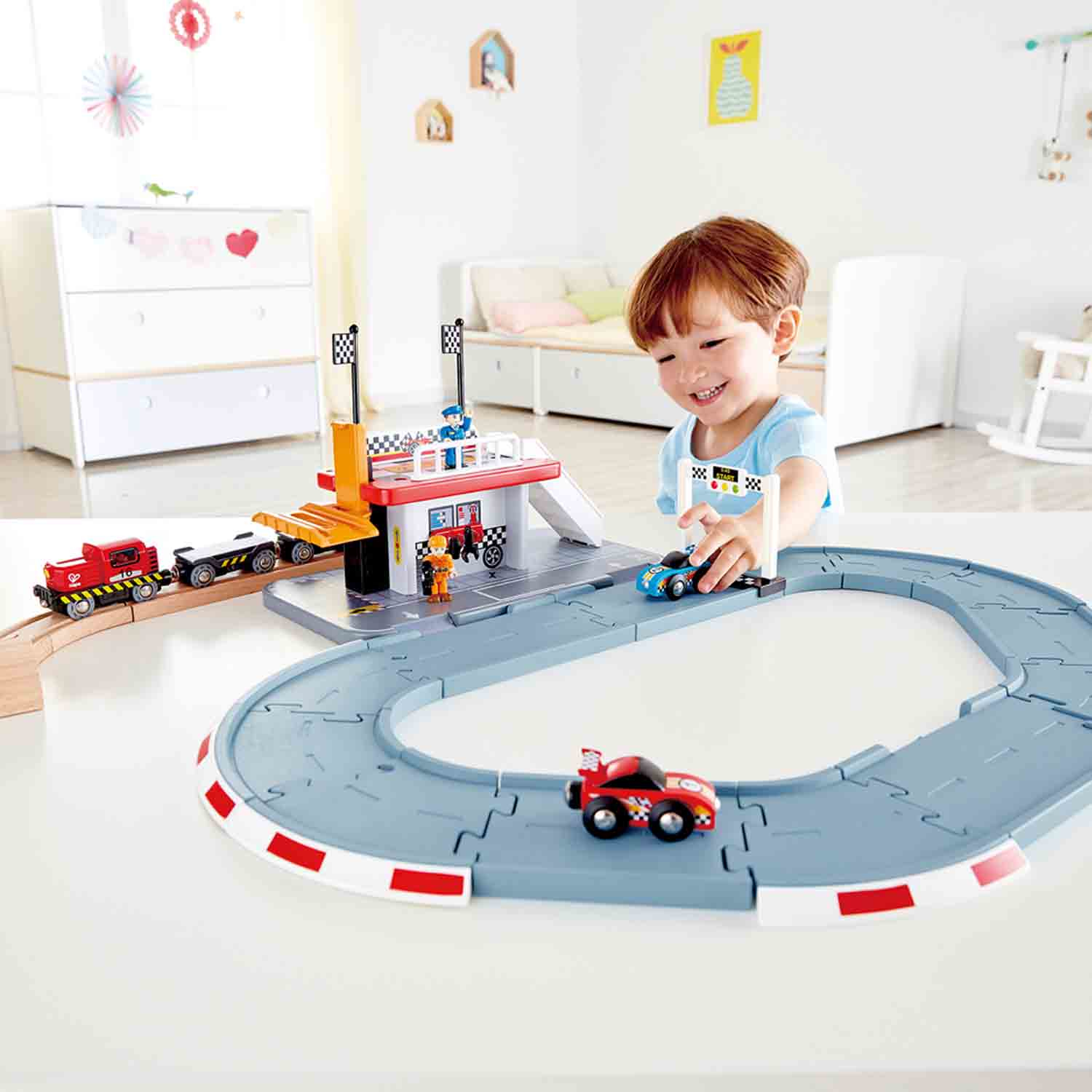 Ein Junge spielt mit einem Spielzeug-Autorennen-Set mit Autos und einer Rennstrecke.