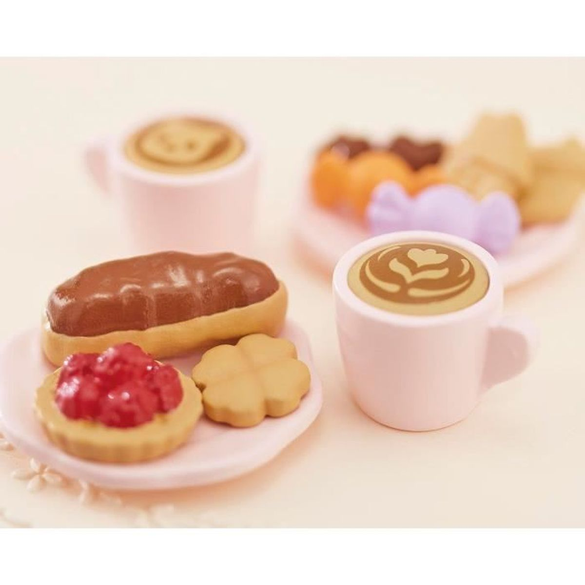 Dos tazas rosas de café con latte art y pasteles en platos.