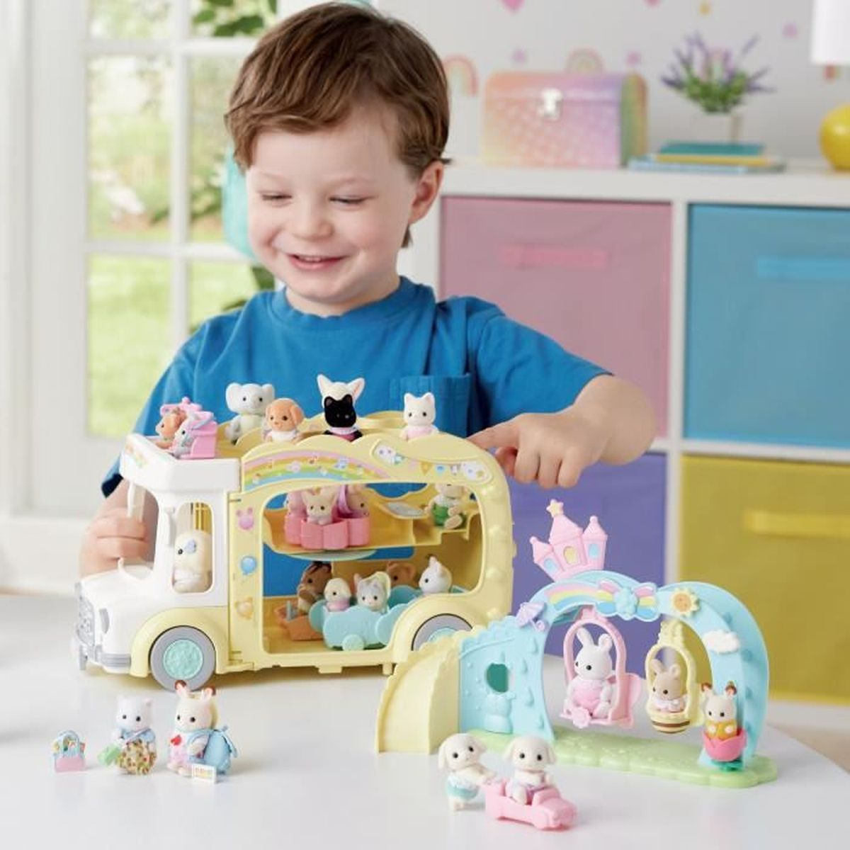 Un niño juega con un autobús de juguete amarillo y un columpio de juguete con figuras de animales.