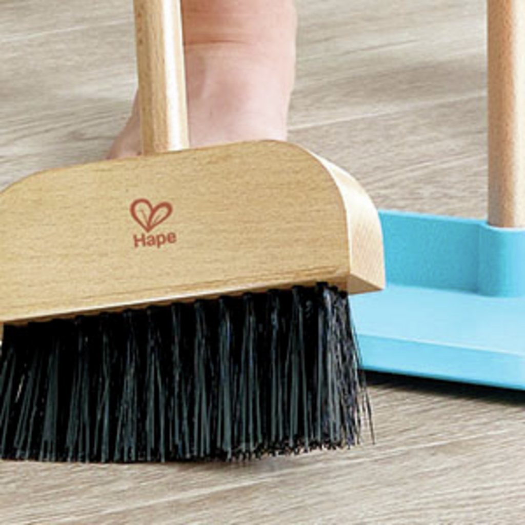 Una escoba de madera con cerdas negras y un recogedor azul sobre un suelo de madera.