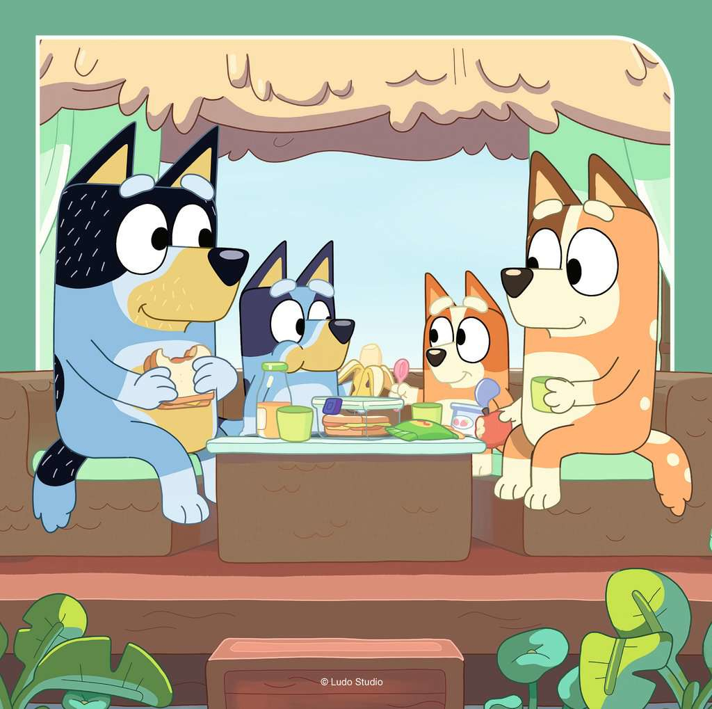 Quattro cani siedono su un divano mangiando.