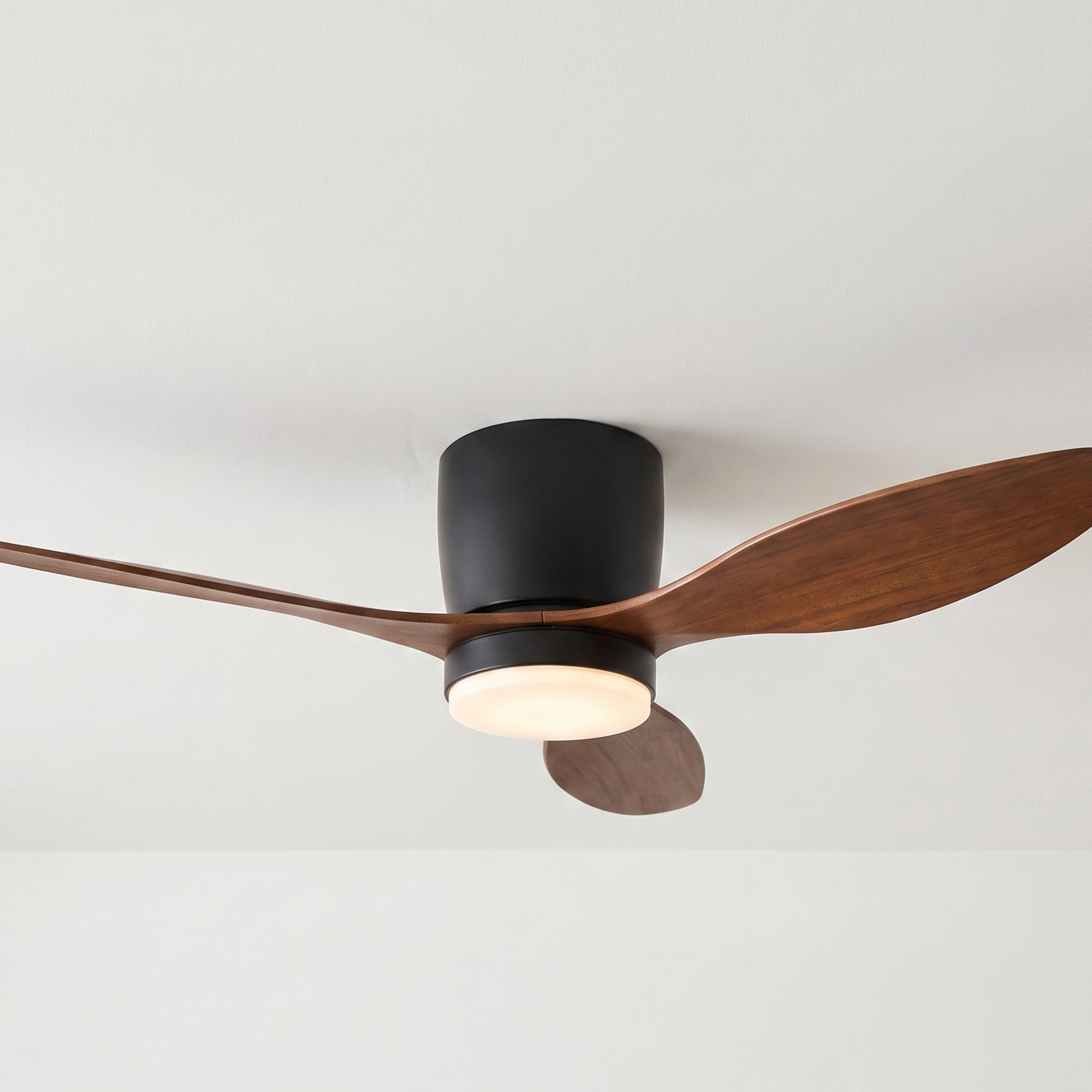 Ventilador de techo con carcasa oscura y aspas de madera, iluminado.